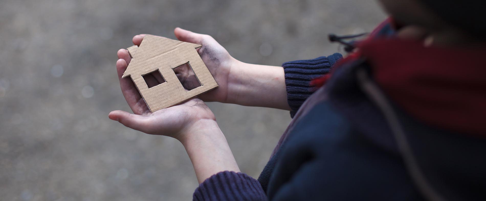 homeless boy holding a cardboard house