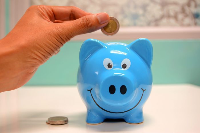 Person putting coins into a piggy bank